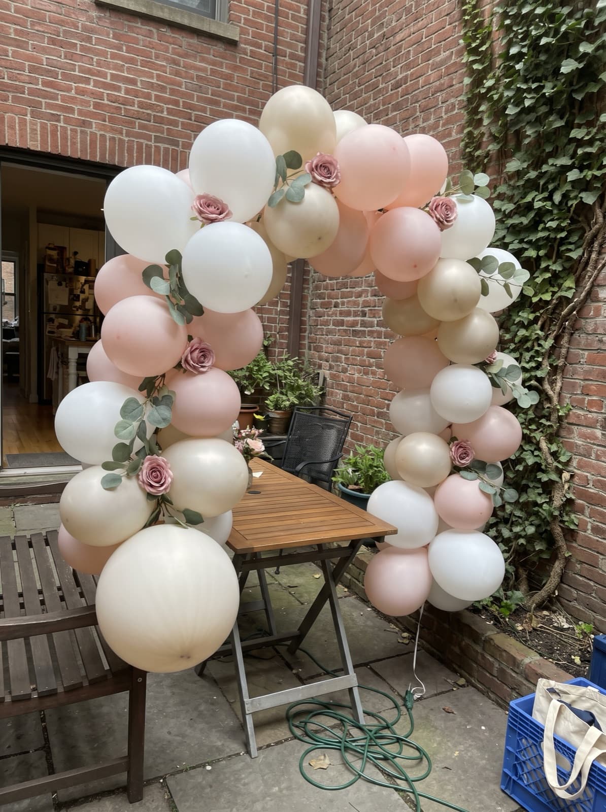 Floral balloon arch with roses and eucalyptus over a garden brunch table