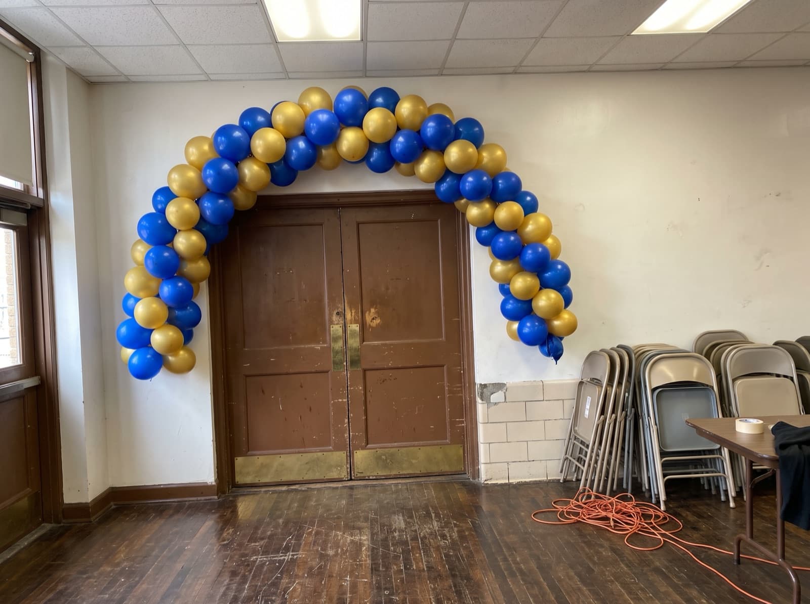 Spiral balloon arch in royal blue and gold over school auditorium doors