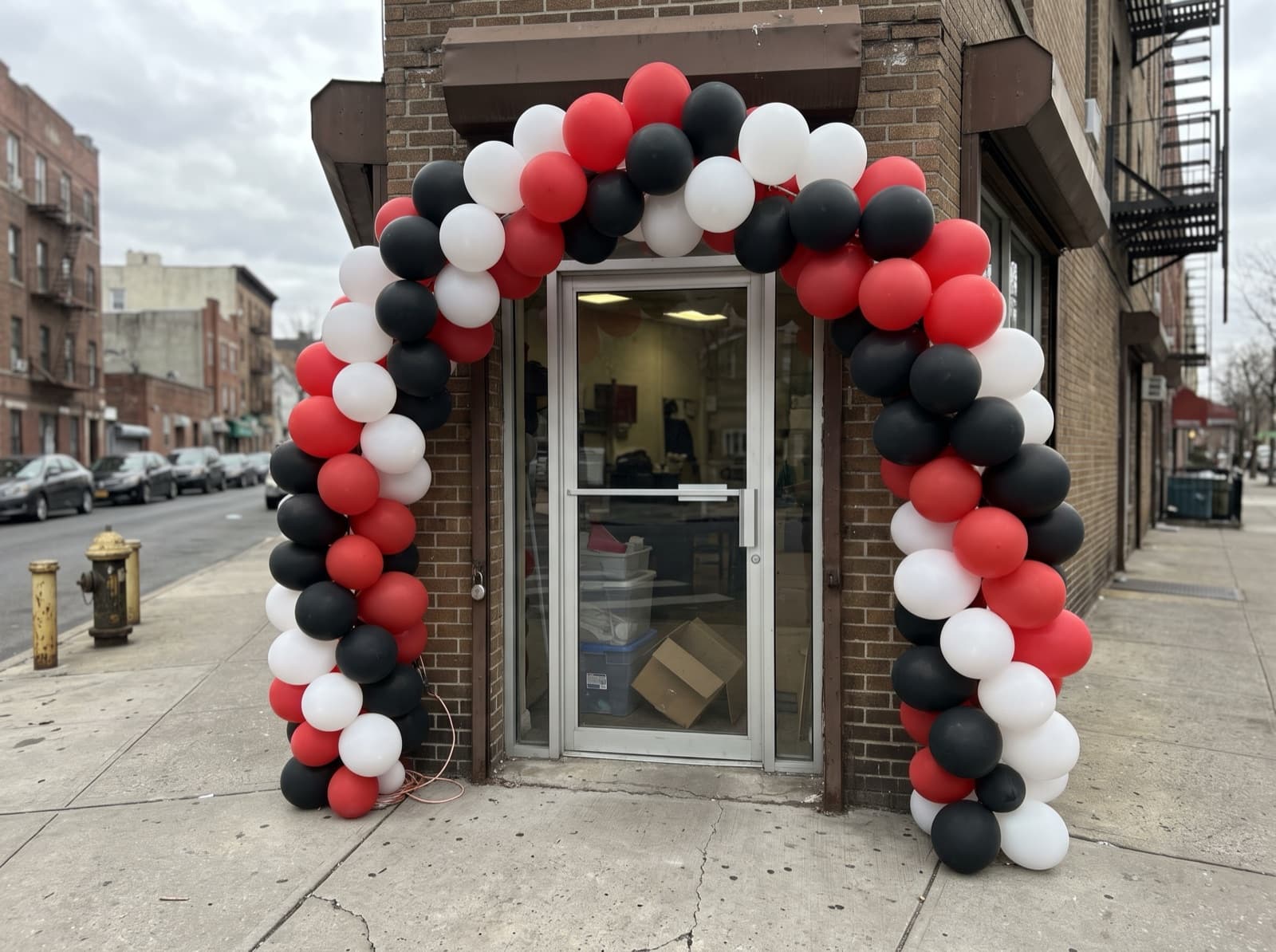 Large red, white and black balloon arch around a shop door