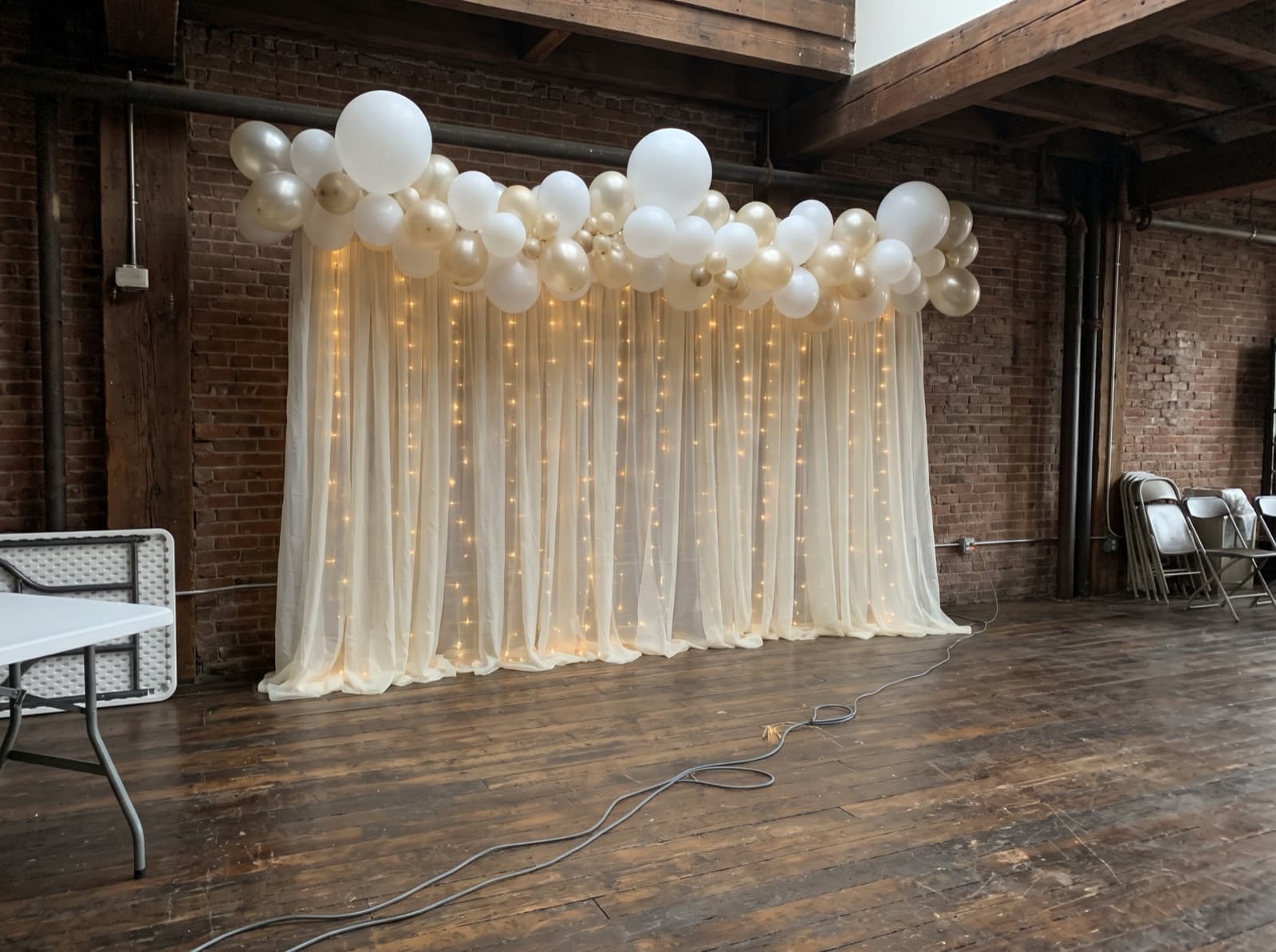Sheer draped backdrop with lights and a champagne balloon garland