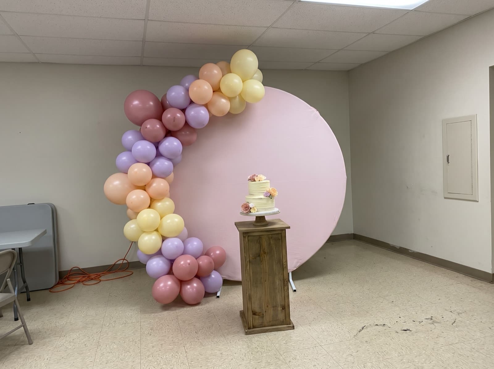 Round pink backdrop with a pastel organic balloon garland
