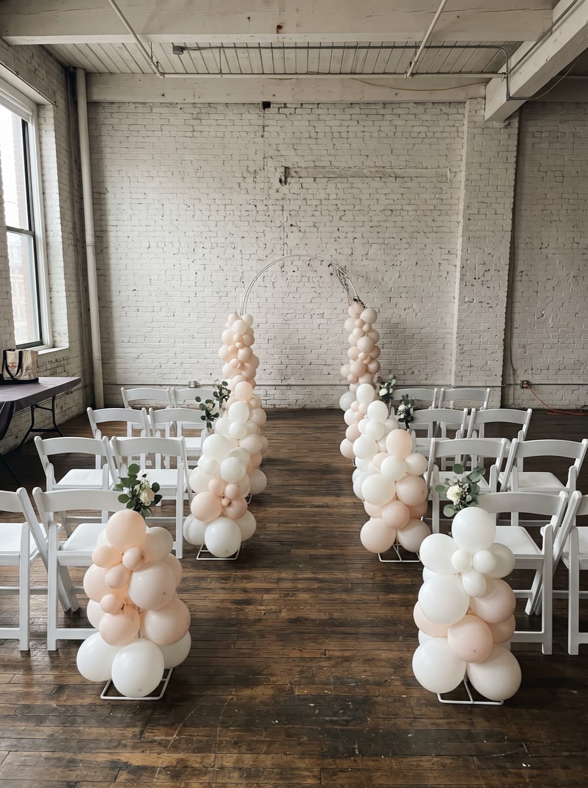 Organic balloon columns lining a ceremony aisle in a loft