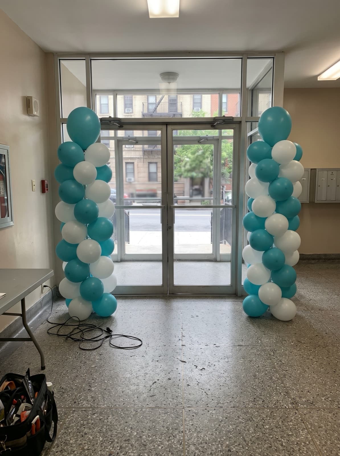 Pair of teal and white spiral balloon columns at a lobby door