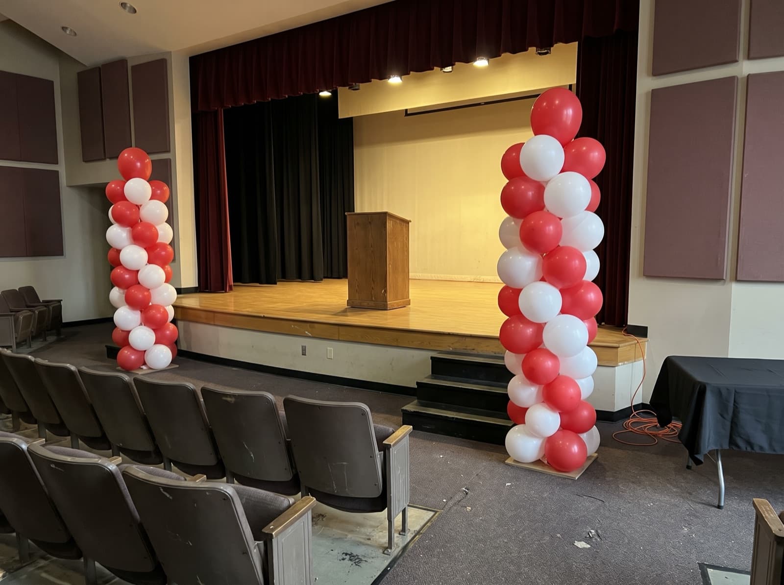 Tall red and white balloon columns beside an auditorium stage