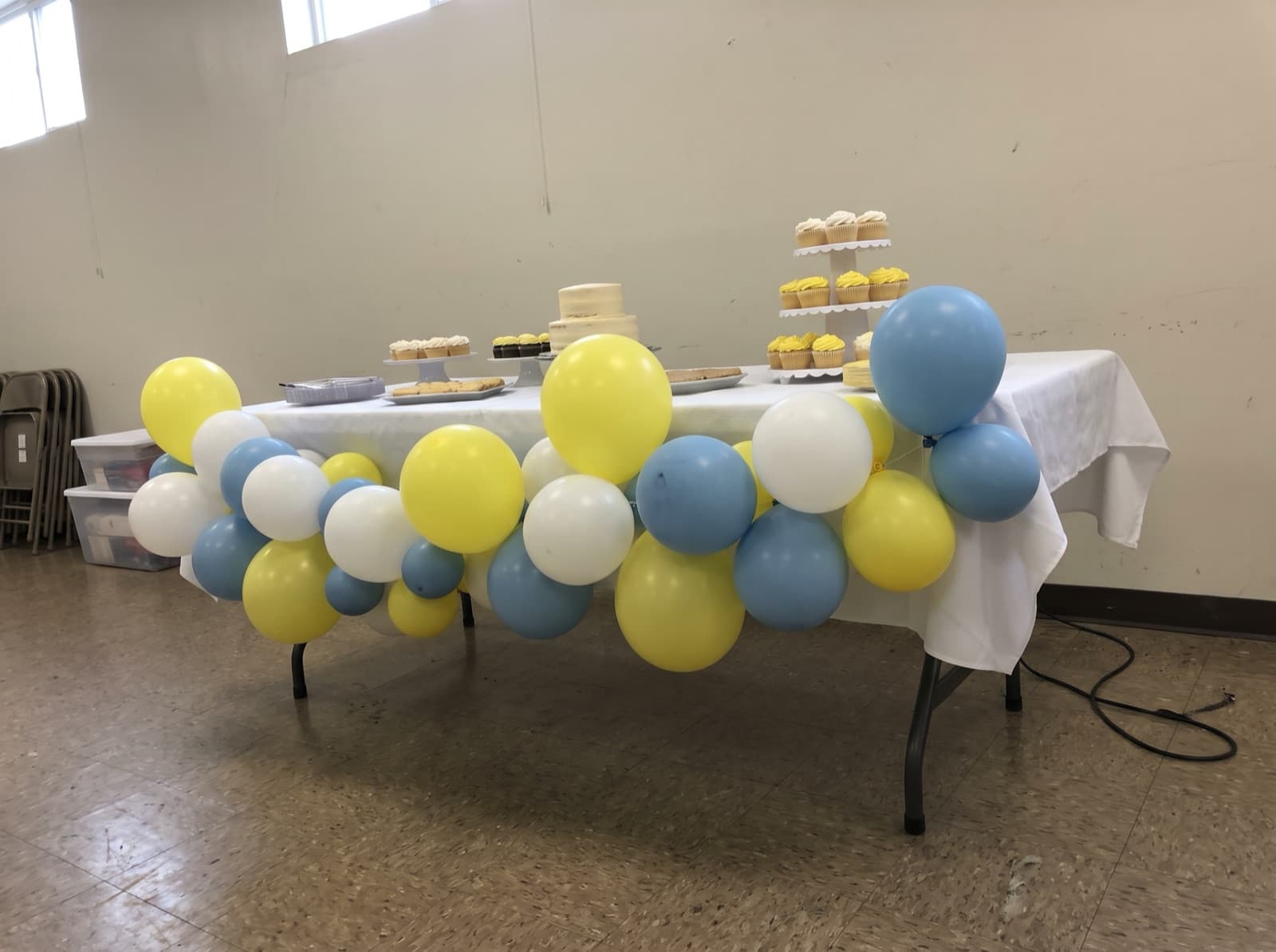 Yellow, white and blue balloon garland across a cake table