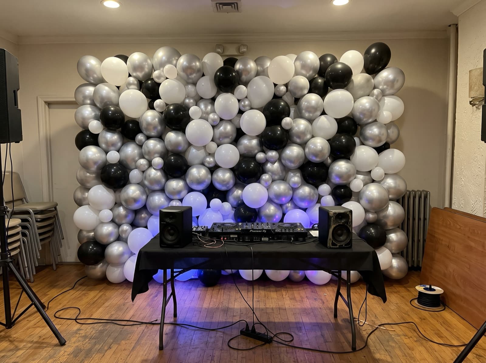 Silver, white and black balloon wall behind a DJ booth