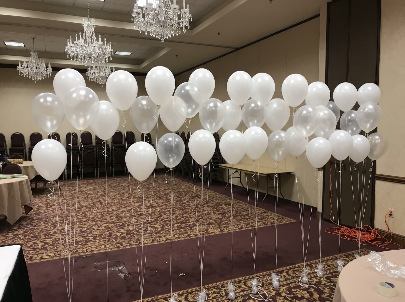 Floating helium balloon wall with ribbons in a ballroom